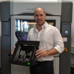 Stefan Kammann vor dem Fortus 450mc 3D-Drucker im ADaM Competence Center mit einer 3D-gedruckten, ESD-konformen Klebevorrichtung .jpg