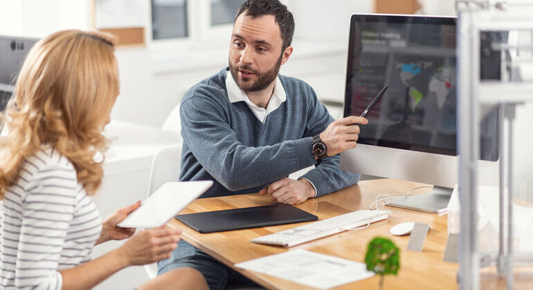 Perfect_presentation._Lively_young_man_pointing_at_the_computer_screen_and_presenting_his_project_to_his_female_boss_while_the_woman_listening_to_him_attentively